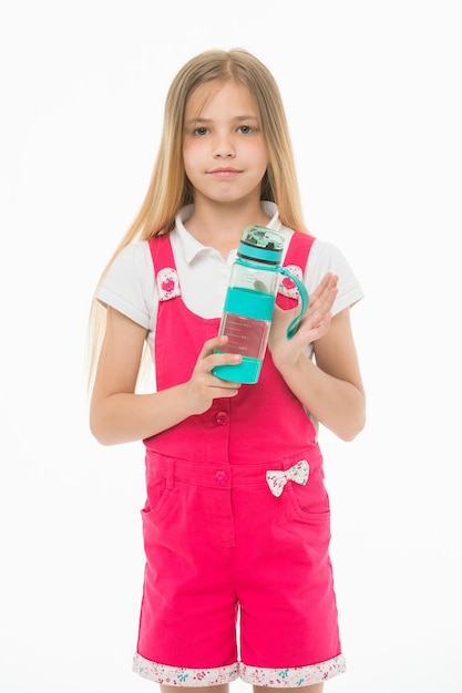 Фото Маленькая девочка с пластиковой бутылкой, изолированной на белом жаждущий ребенок в розовом комбинезоне держит бутылку с водой питьевая вода для здоровья жажда и обезвоживание детская активность и энергия