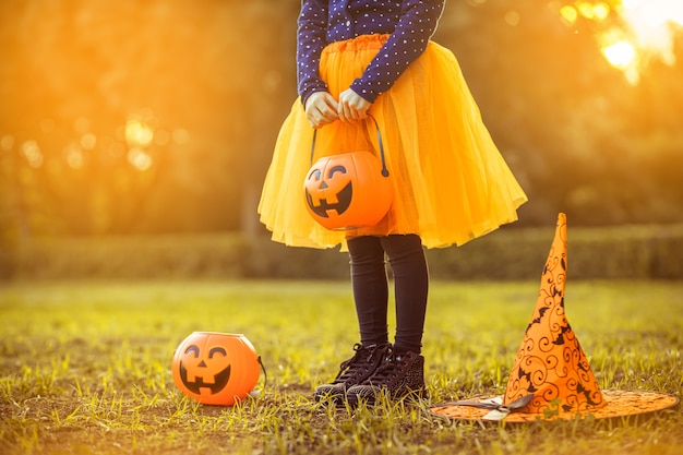 Foto bambina con il secchio di caramelle di zucca all'aperto