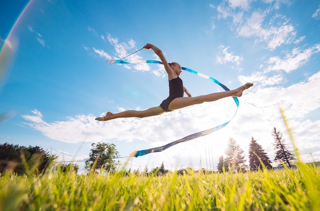 A little girl with a ribbon jumping on the grass.