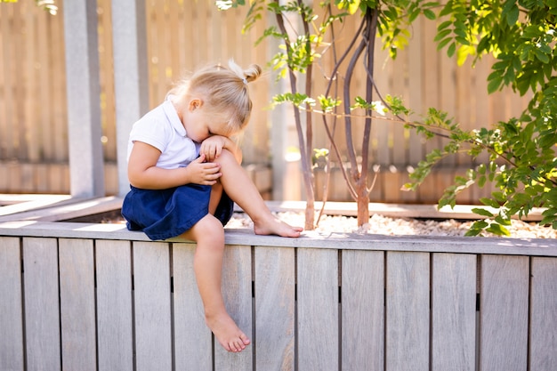 Little girl with sad expression outside. Sad little blonde girl