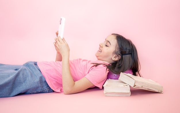 분홍색 배경 복사 공간에 손에 스마트폰을 들고 있는 어린 소녀