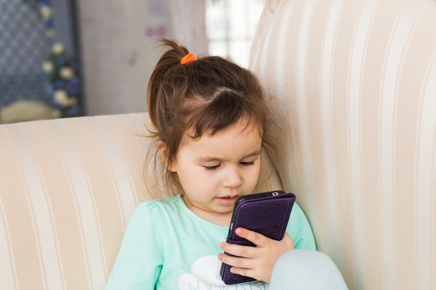 ベッドに横たわって、就寝時にスマートフォンを持つ少女