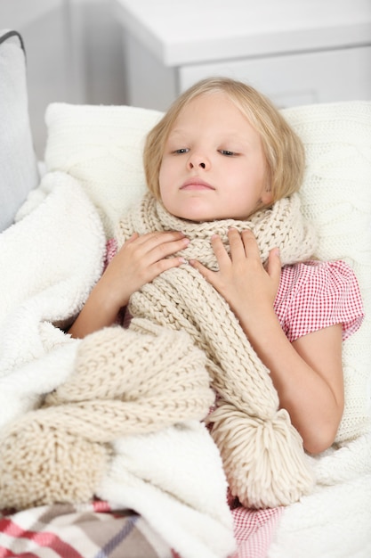 Little girl with sore throat lying on the bed