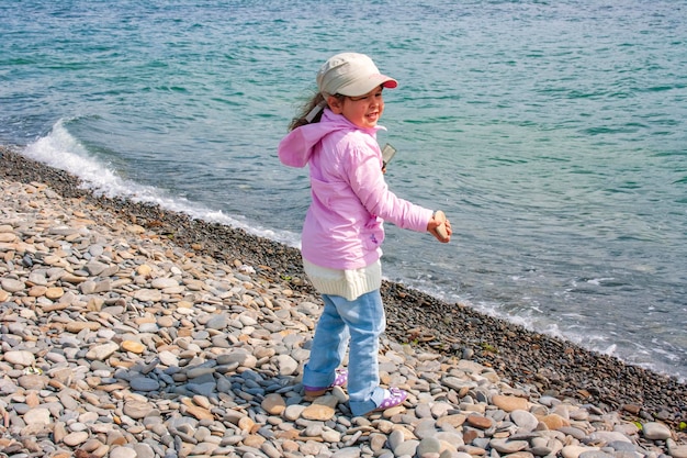 해변에서 손에 돌을 들고 있는 어린 소녀
