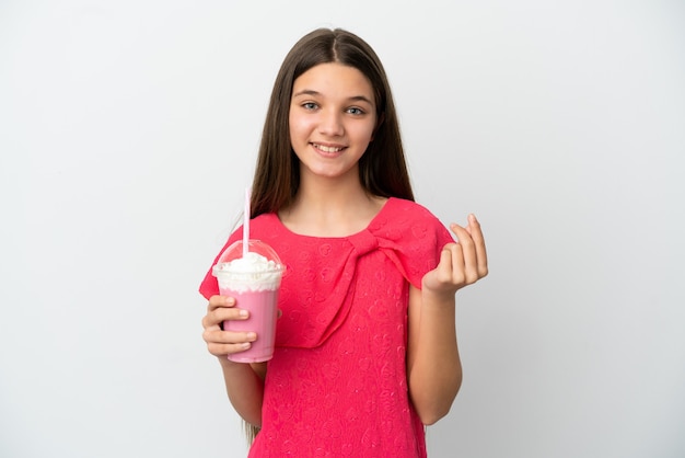 Little girl with strawberry milkshake over isolated white background making money gesture