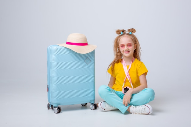 Little girl with a suitcase traveler on a white background