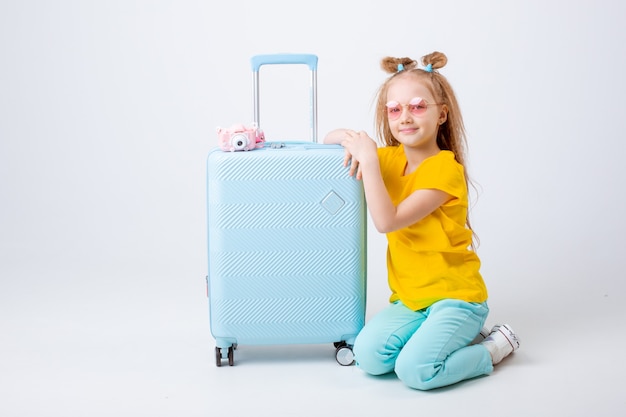 Little girl with a suitcase traveler on a white background