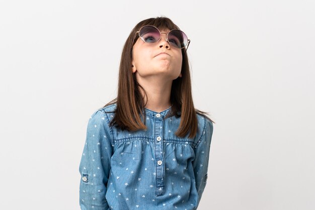 Little girl with sunglasses isolated on white background and looking up