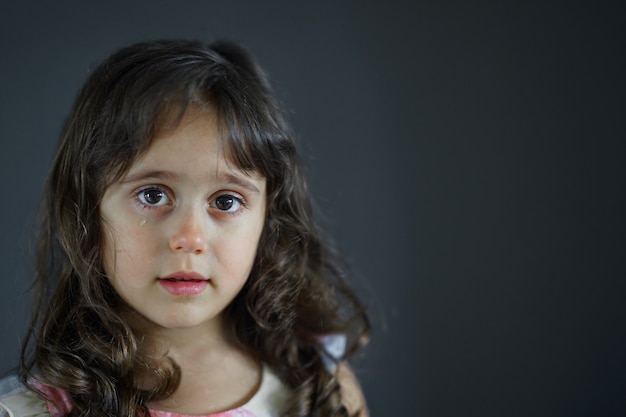 A little girl with a tear under her eye looks straight