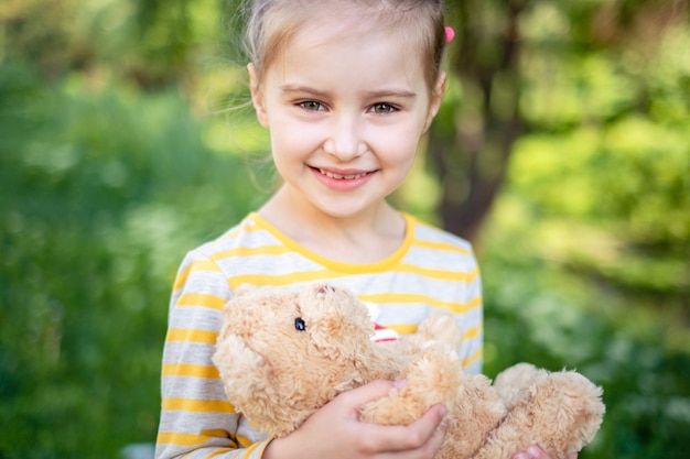 Little girl with teddy bear in park