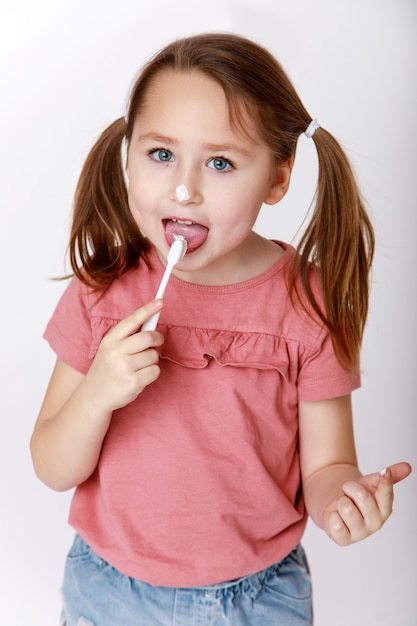 little girl with toothbrush brushing teeth tasting toothpaste