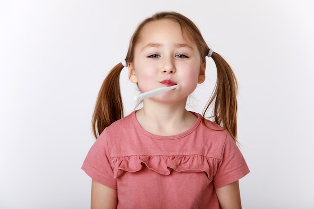 Bambina con uno spazzolino da denti in bocca