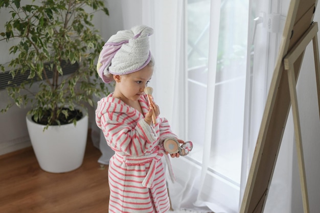 A little girl with a towel on her head doing makeup