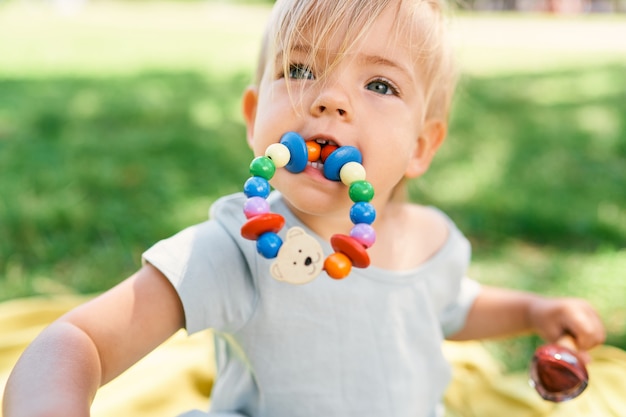 Little girl with a toy bracelet in her mouth holds an ice cream in her hand portrait