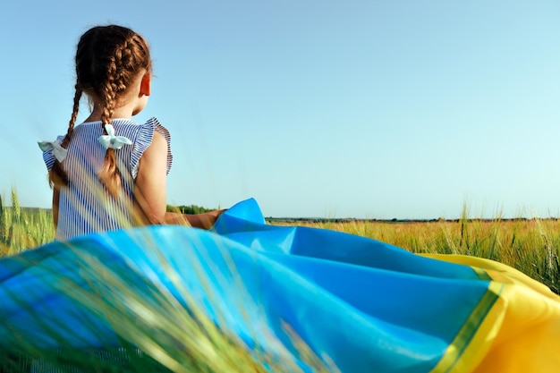 Little girl with Ukrainian flag in wheat fieldHappy boy celebrating Independence Day