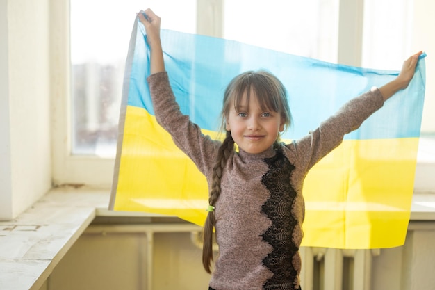 Little girl with Ukrainian flag on white background