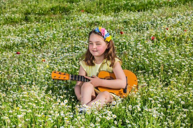 Little girl with ukulele resting in field