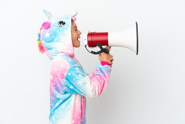 Bambina con pigiama unicorno isolato su sfondo bianco che grida attraverso un megafono