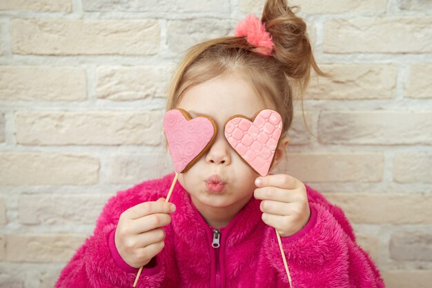 Photo little girl with valentine heart shaped cookies in her hands. love concept