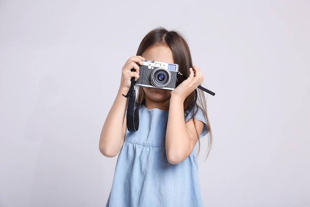 Bambina con macchina fotografica d'epoca su sfondo chiaro