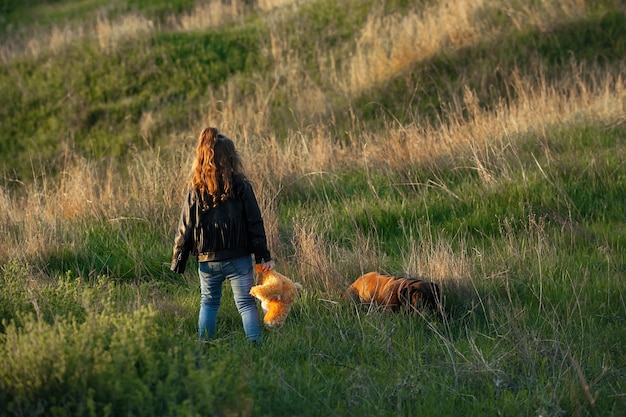 little girl with wavy hair on a walk in the evening in nature with a pet dog