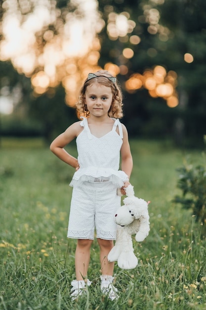 A little girl with a white bear in the open-air mine at sunset