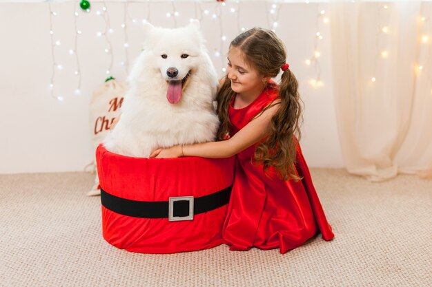 Bambina con cane samoiedo bianco seduto nella casella di santa