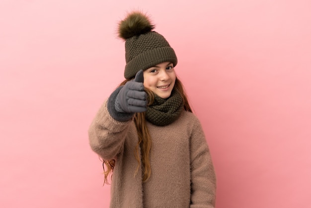 Little girl with winter hat isolated on pink background shaking hands for closing a good deal