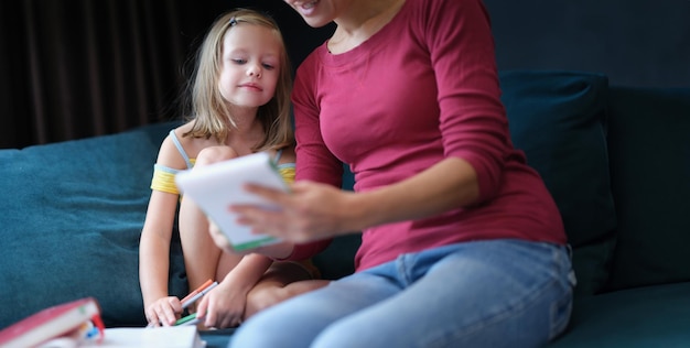 Little girl and woman sitting on couch with textbooks