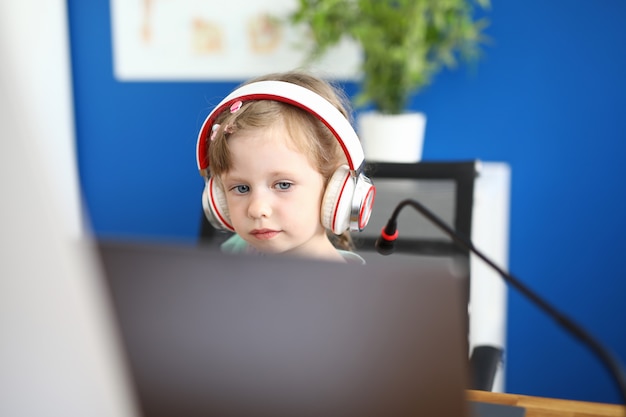 Little girl work with laptop against home background.