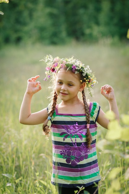 little girl in a wreath of wild flowers in summer