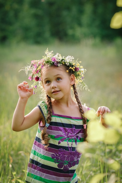 little girl in a wreath of wild flowers in summer