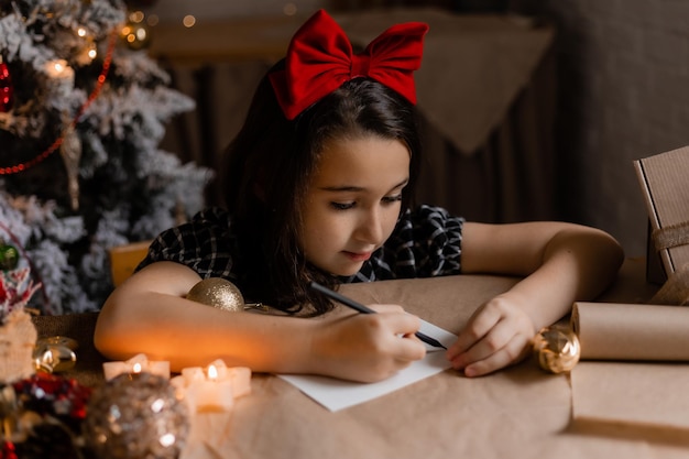 Photo little girl writes a letter with wishes to santa claus