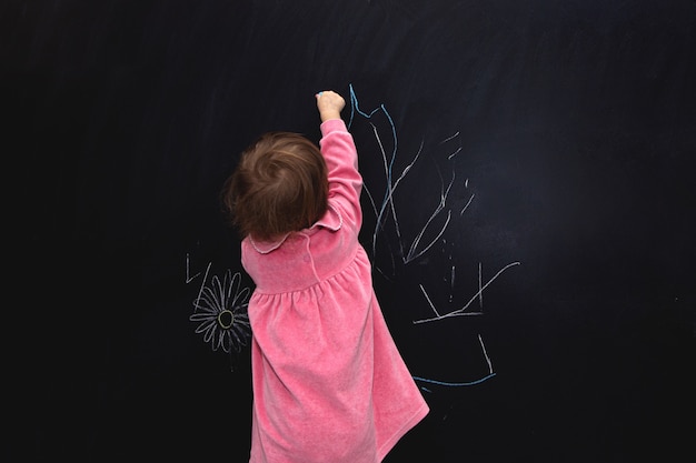 Little girl writing something on blackboard