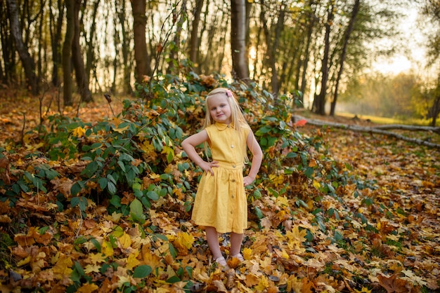 Little girl in a yellow dress in the autumn park.