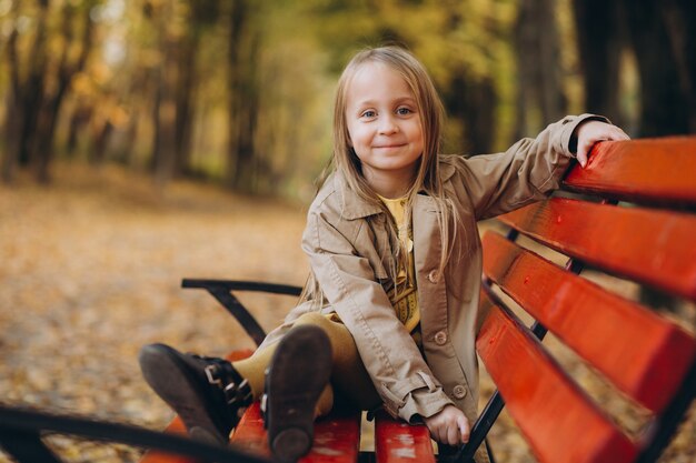 A little girl in a yellow dress and beige coat walk in autumn Park