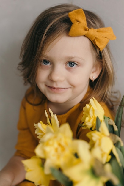 Little girl in a yellow dress with a beautiful bouquet of narcissus flower