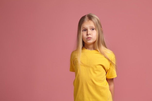 Little girl in a yellow t-shirt. looks puzzled