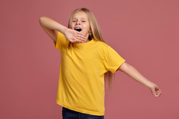 Little girl in a yellow t-shirt. stretches and yawns