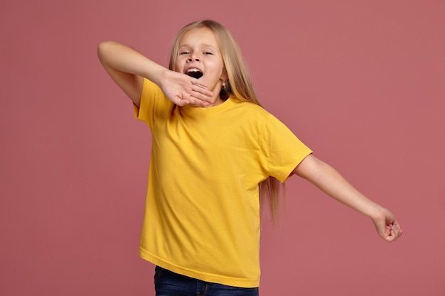 黄色のTシャツを着た少女。ストレッチとあくび