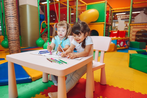 Little girls are sitting at a table and drawing in a children's play center children's creativity