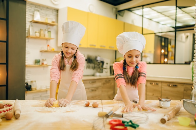Little girls chefs crumple the dough