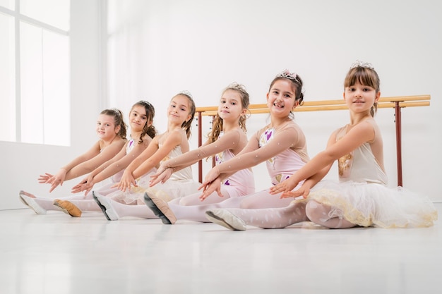 Little girls in dresses posing together at the ballet class. Looking at camera.