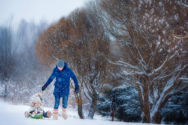 Little girls enjoying sledding. Father sledding his little adorable daughters.