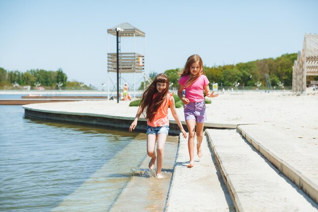 Little girls have fun on the city beach run on the water on the lake