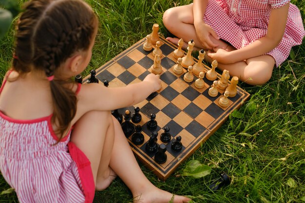 Le bambine imparano a giocare a scacchi in giardino su una vecchia scacchiera