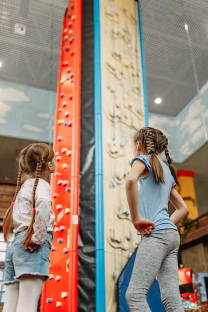 Little girls looks on climbing wall, game center