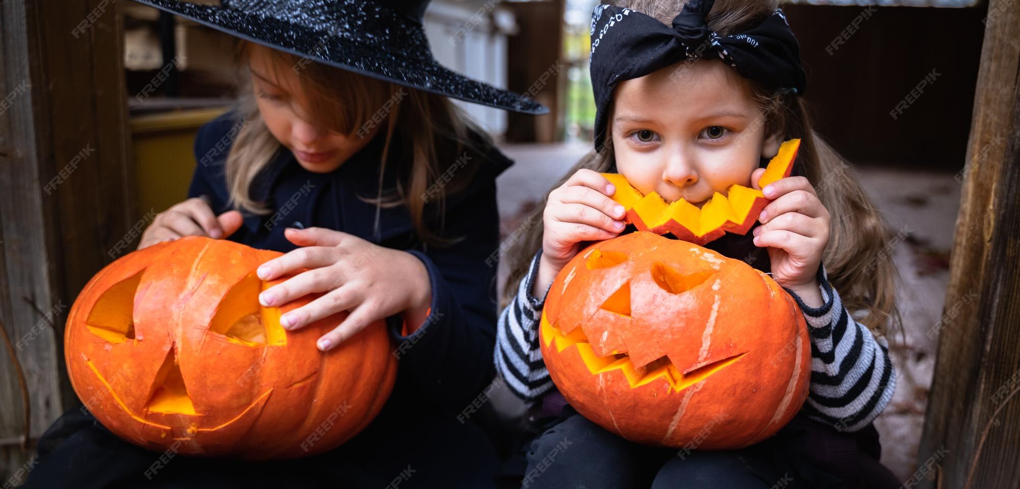 小さな女の子はハロウィーンの休日のお祝いのために大きなカボチャからジャコランタンを作ります魔女の衣装の帽子のコートナイフで切る種と一緒にパルプを取り出します野外活動の裏庭子供のパーティー プレミアム写真