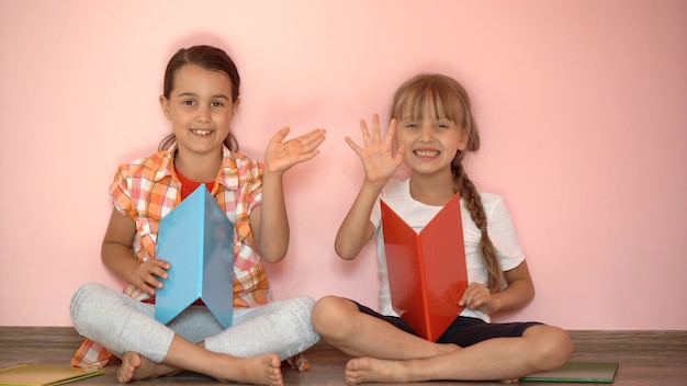 Bambine che leggono un libro in soggiorno. studentesse intelligenti che fanno i compiti dopo la scuola. educazione e didattica a distanza per i bambini. istruzione domiciliare durante la quarantena. resta a casa con l'intrattenimento.