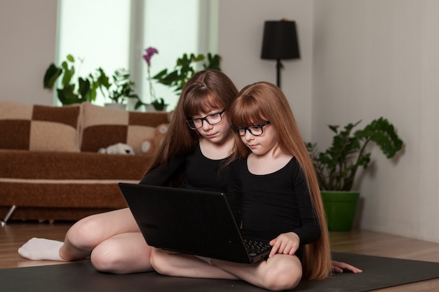 Little girls sisters hold an online lesson gymnastics at home